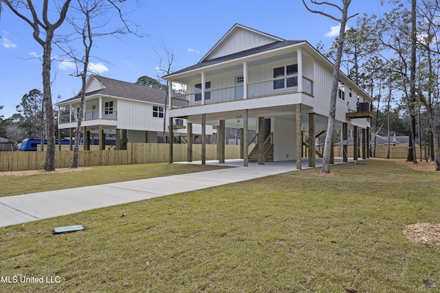 beach home with a shingled roof, stairs, a front yard, a carport, and driveway