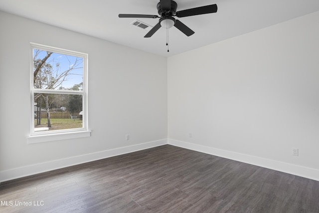 spare room with visible vents, plenty of natural light, baseboards, and dark wood finished floors