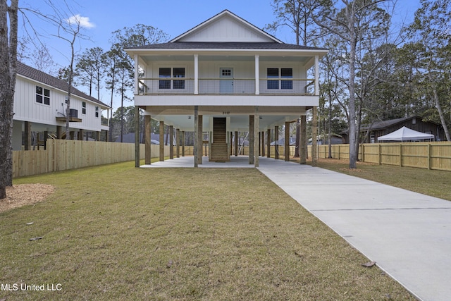 view of front of home with board and batten siding, stairway, a front yard, roof with shingles, and driveway