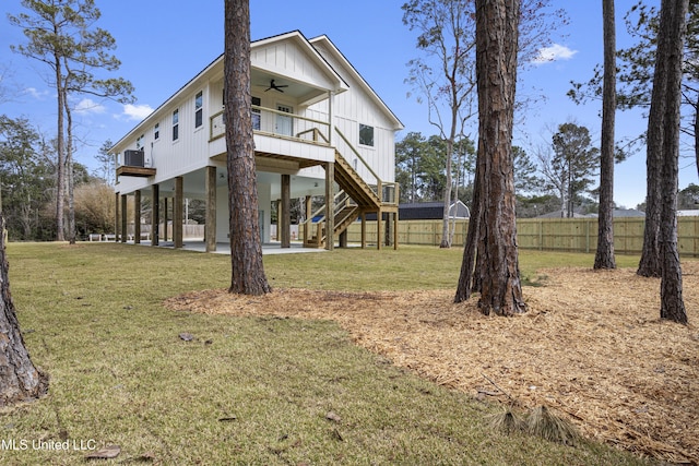 back of house with a lawn, a ceiling fan, fence, stairway, and a carport