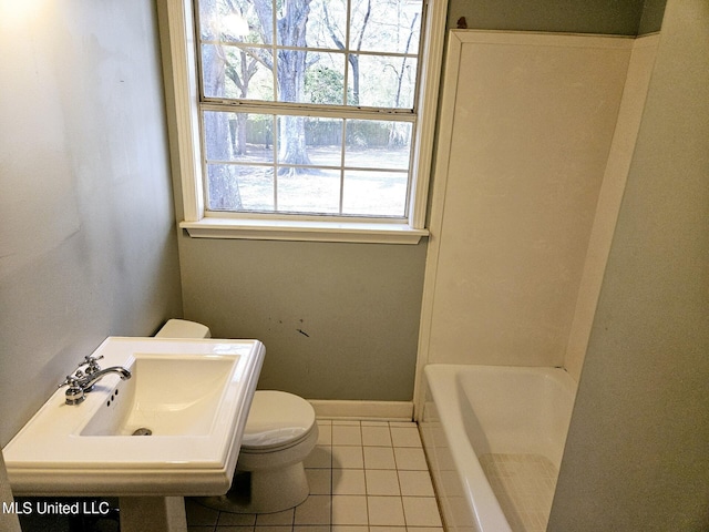 bathroom with tile patterned flooring, a tub to relax in, sink, and toilet