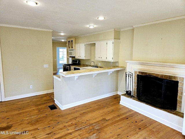 kitchen featuring stainless steel stove, white cabinetry, sink, a breakfast bar area, and kitchen peninsula