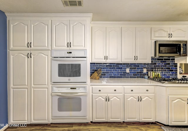 911 Newitt Vick Dr, Vicksburg, MS 39183 - kitchen with stainless steel appliances, dark wood finished floors, white cabinets, light countertops, and tasteful backsplash
