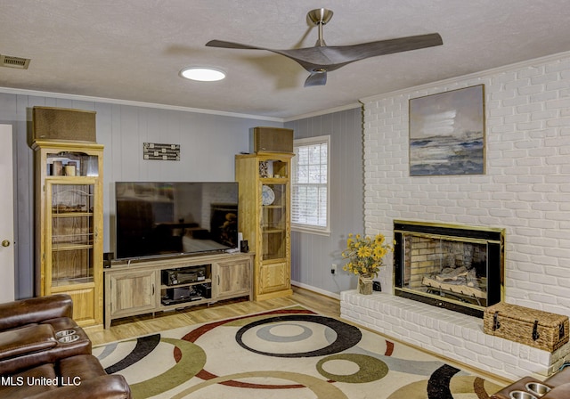 911 Newitt Vick Dr, Vicksburg, MS 39183 - living room featuring ornamental molding, light wood-type flooring, ceiling fan, a fireplace, and a textured ceiling