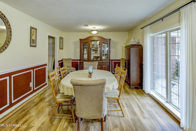 911 Newitt Vick Dr, Vicksburg, MS 39183 - dining space featuring a wainscoted wall, plenty of natural light, light wood-style flooring, and a decorative wall