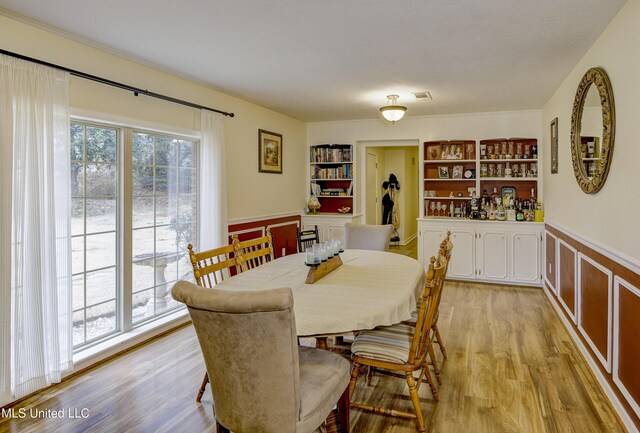 911 Newitt Vick Dr, Vicksburg, MS 39183 - dining room with a wainscoted wall, light wood-style floors, and built in shelves