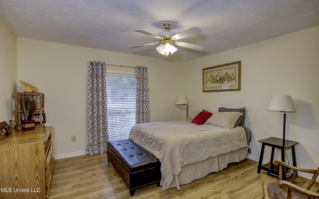 911 Newitt Vick Dr, Vicksburg, MS 39183 - bedroom featuring light wood-style floors, baseboards, a textured ceiling, and a ceiling fan