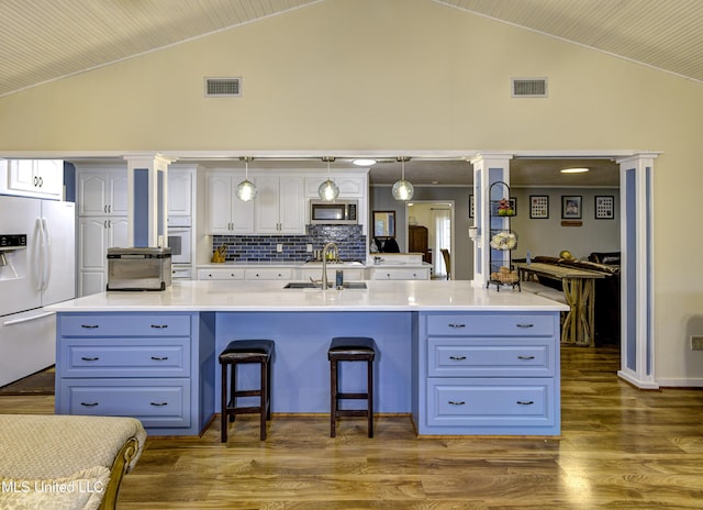 911 Newitt Vick Dr, Vicksburg, MS 39183 - kitchen featuring white refrigerator with ice dispenser, stainless steel microwave, white cabinetry, a kitchen bar, and decorative backsplash