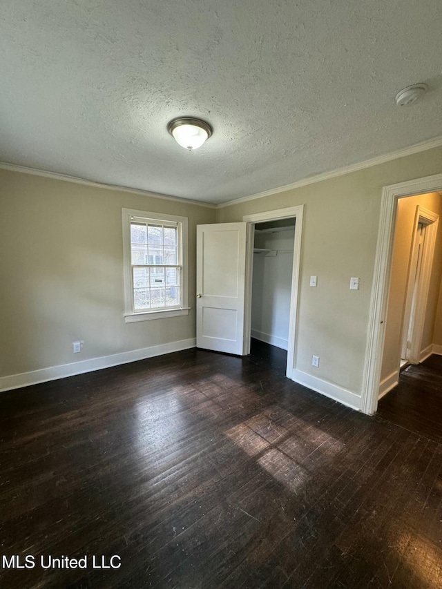 unfurnished bedroom with ornamental molding, a textured ceiling, a closet, and dark wood-type flooring