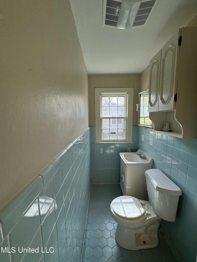 bathroom with tile patterned flooring, vanity, tile walls, and toilet