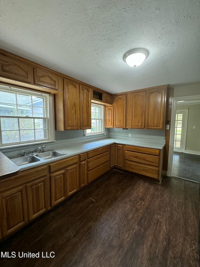 kitchen with a textured ceiling, dark wood-type flooring, and sink