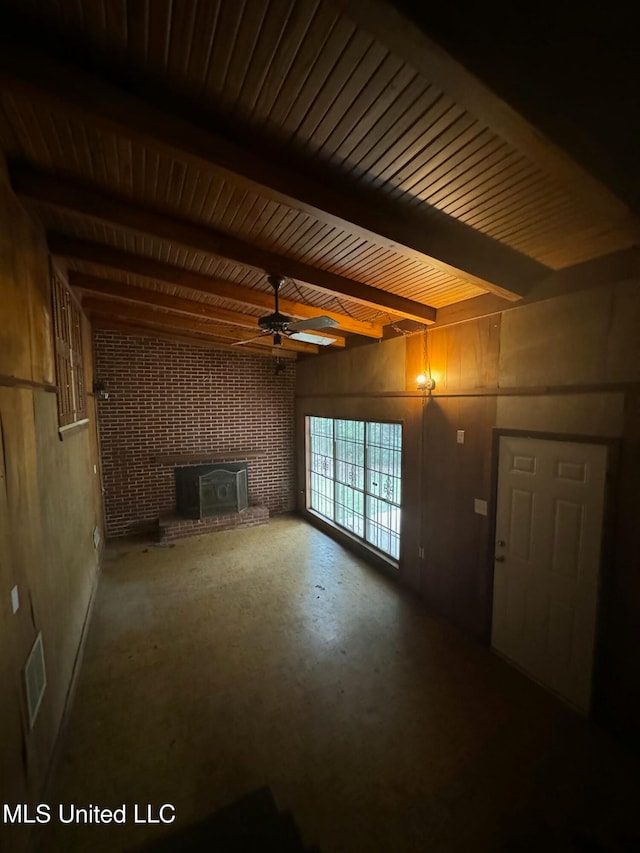 unfurnished living room featuring ceiling fan, beam ceiling, and a wood stove