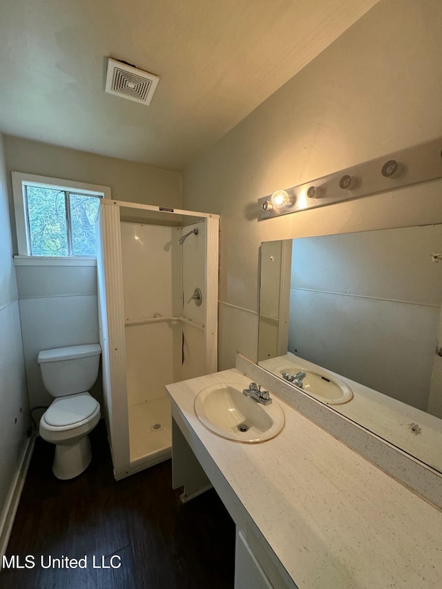 bathroom featuring toilet, hardwood / wood-style floors, vanity, and walk in shower