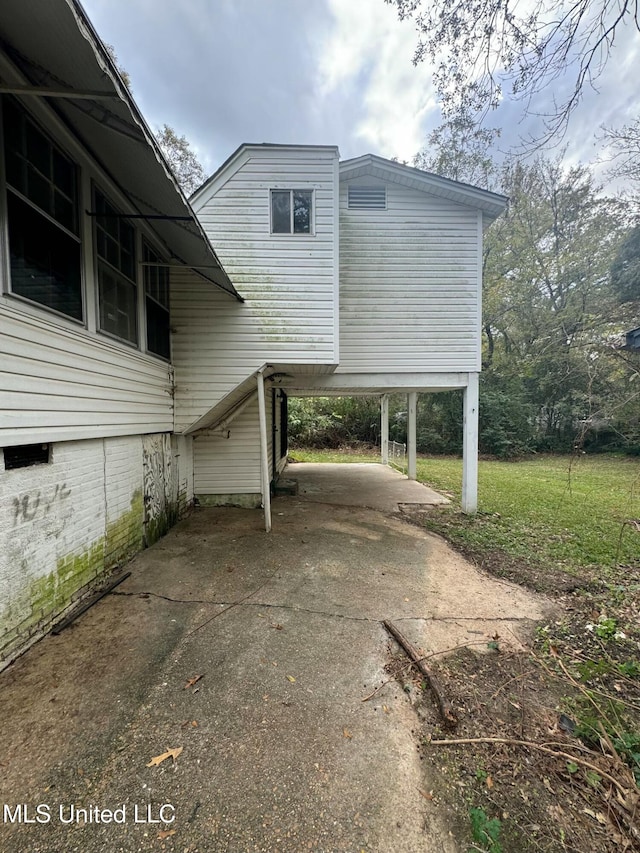 view of side of property featuring a lawn and a carport