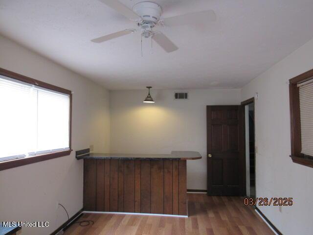 kitchen featuring a ceiling fan, visible vents, a peninsula, and wood finished floors