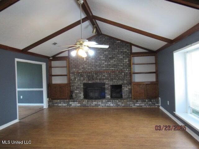 unfurnished living room with wood finished floors, vaulted ceiling with beams, a fireplace, baseboards, and a ceiling fan