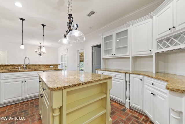 11541 Briarstone Pl, Gulfport, MS 39503 - kitchen with brick flooring, a center island, glass insert cabinets, light stone countertops, and crown molding
