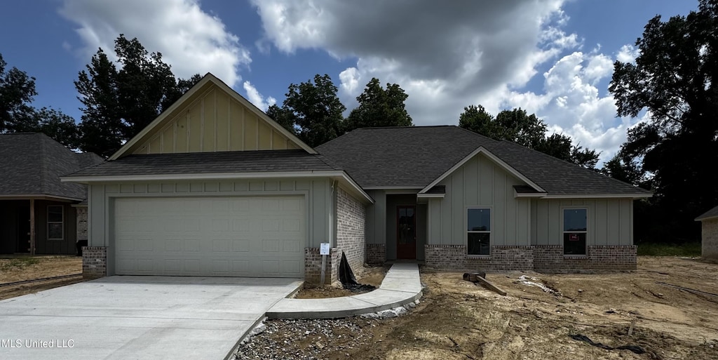 345 Willow Way, Canton, MS 39046 - view of front facade with board and batten siding, a garage, concrete driveway, a shingled roof, and brick siding