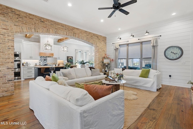 living area featuring arched walkways, a healthy amount of sunlight, a ceiling fan, and hardwood / wood-style floors