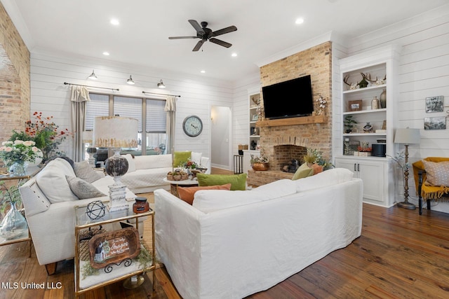 living room with wood finished floors, a ceiling fan, recessed lighting, crown molding, and a brick fireplace