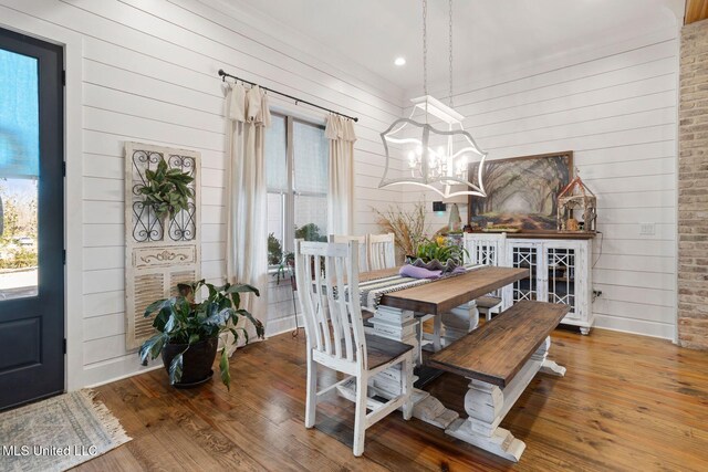 dining area featuring a notable chandelier, wood finished floors, wood walls, and a wealth of natural light