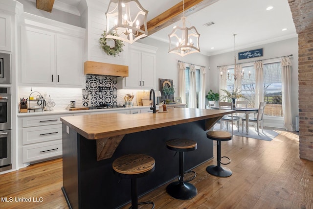 kitchen with visible vents, a notable chandelier, tasteful backsplash, butcher block counters, and light wood finished floors