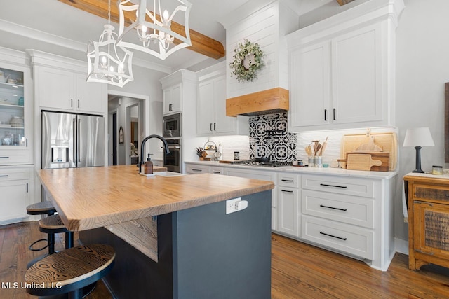 kitchen with dark wood-type flooring, a center island with sink, a sink, backsplash, and stainless steel appliances