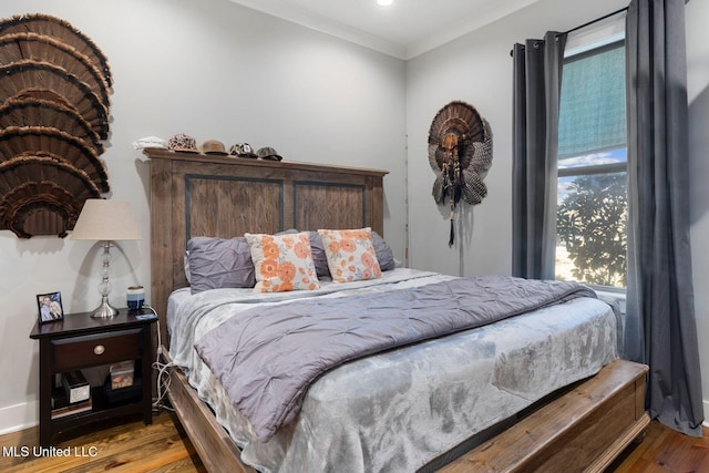 bedroom with crown molding, baseboards, and wood finished floors