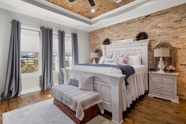 bedroom with brick wall, a tray ceiling, ceiling fan, dark wood-type flooring, and wood ceiling