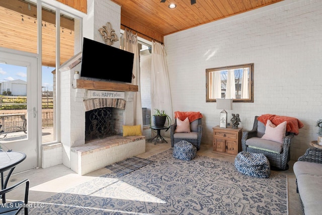 living area featuring plenty of natural light, wood ceiling, and brick wall