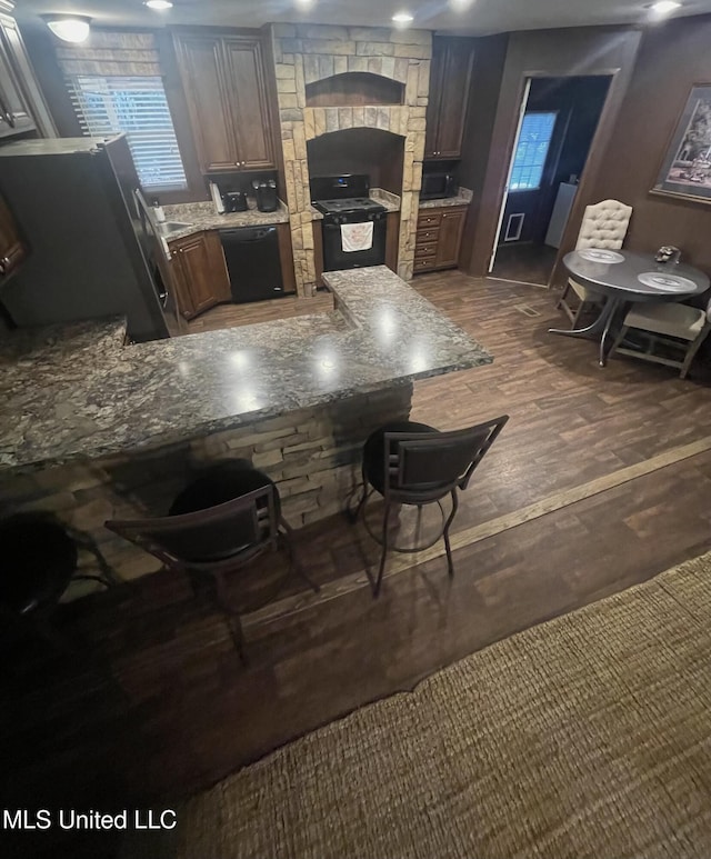 43 White Oak Dr, Natchez, MS 39120 - kitchen with black appliances, dark wood-style floors, light stone counters, a kitchen breakfast bar, and a sink