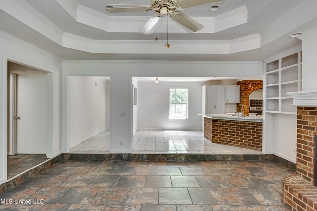 354 Lakeway Dr, Brandon, MS 39047 - unfurnished living room with ornamental molding, a ceiling fan, stone tile floors, a raised ceiling, and baseboards