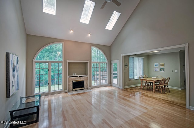 living room featuring ceiling fan, high vaulted ceiling, light hardwood / wood-style flooring, and a fireplace