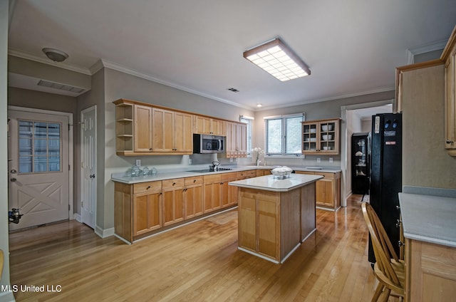 kitchen with black stovetop, a kitchen island, light hardwood / wood-style flooring, and crown molding