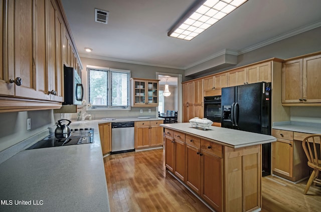 kitchen with a kitchen island, ornamental molding, black appliances, and light hardwood / wood-style floors