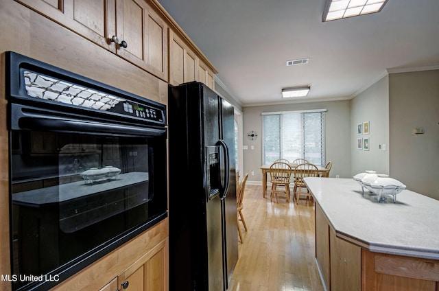 kitchen with a kitchen island, ornamental molding, black appliances, and light hardwood / wood-style floors