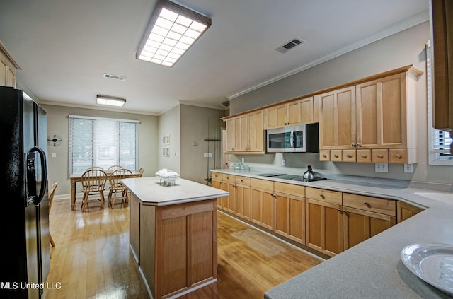 kitchen with light hardwood / wood-style floors, a center island, black appliances, and crown molding