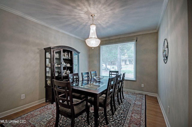 dining room with a notable chandelier, hardwood / wood-style flooring, and ornamental molding