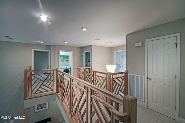 hallway featuring an inviting chandelier, washer / clothes dryer, and carpet flooring