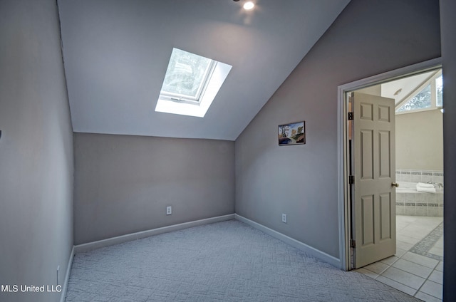 bonus room featuring lofted ceiling with skylight and light colored carpet