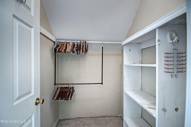 spacious closet featuring light colored carpet and vaulted ceiling