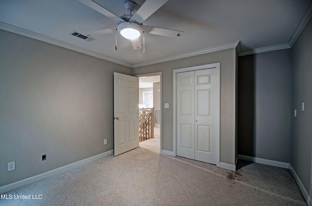 unfurnished bedroom featuring a closet, ornamental molding, light colored carpet, and ceiling fan