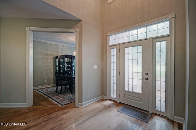 foyer entrance with crown molding and light hardwood / wood-style flooring