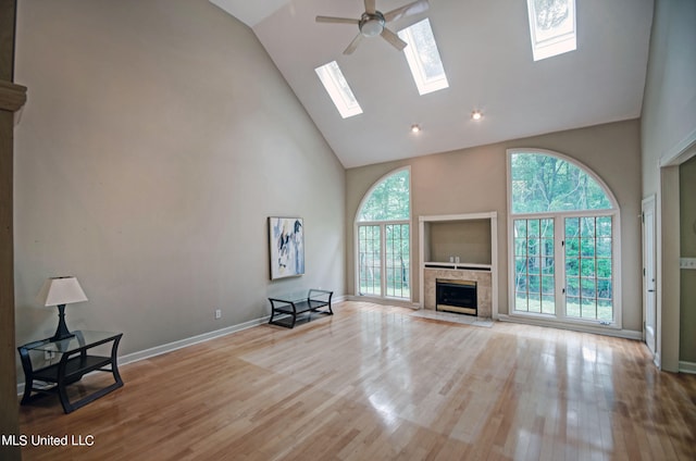 unfurnished living room with light hardwood / wood-style flooring, high vaulted ceiling, a fireplace, and ceiling fan