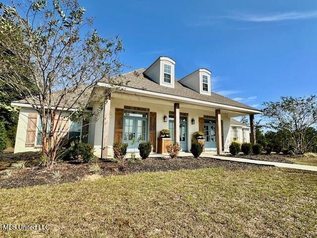 view of front facade with french doors, covered porch, and a front lawn