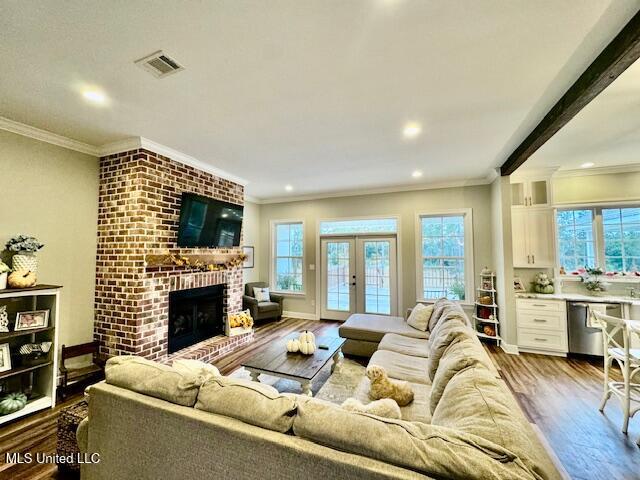 living room featuring light hardwood / wood-style flooring, french doors, a fireplace, and crown molding