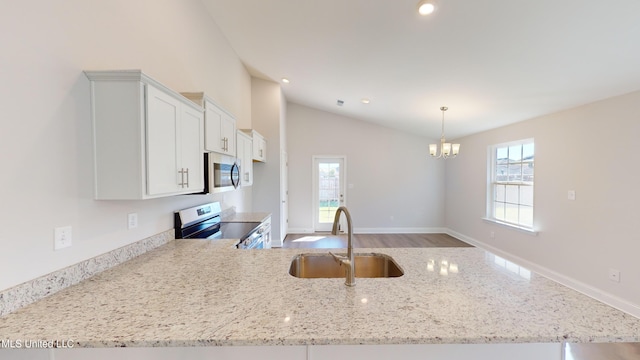 kitchen with sink, wood-type flooring, lofted ceiling, white cabinets, and appliances with stainless steel finishes