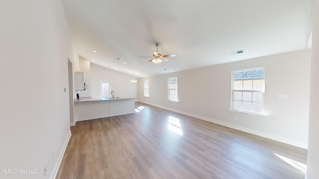 unfurnished living room with hardwood / wood-style flooring, vaulted ceiling, ceiling fan, and sink