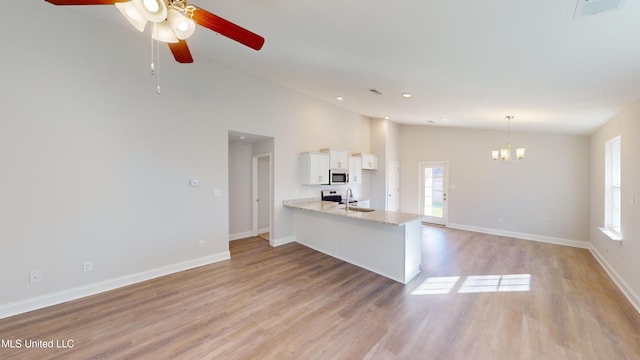 interior space with kitchen peninsula, appliances with stainless steel finishes, light hardwood / wood-style floors, white cabinetry, and lofted ceiling