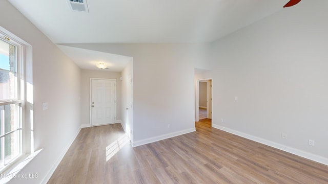 empty room with light hardwood / wood-style floors and lofted ceiling